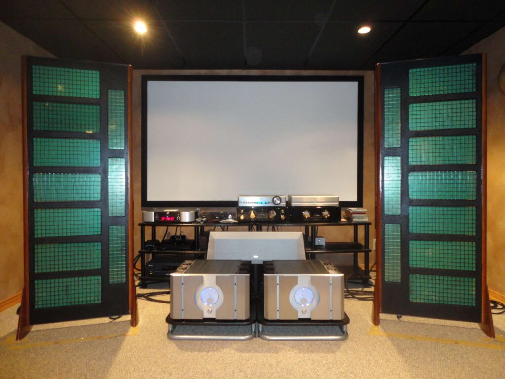 High-fidelity audio setup featuring two unique speakers, an amplifier, and a large projection screen, showcasing an immersive listening experience.